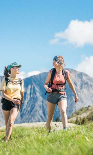 Deux randonneuses marchant en montagne avec panorama sur les Aiguillettes