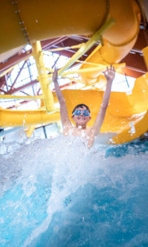Enfant enthousiaste sortant du grand toboggan de la piscine de Vaujany