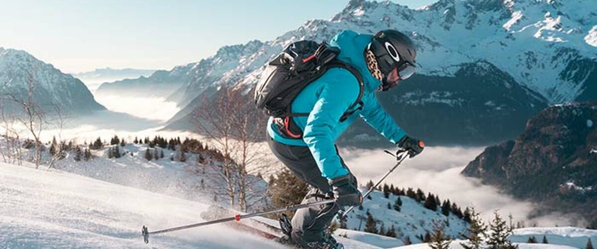Skieur glissant sur les pentes enneigées de Vaujany face aux massifs recouverts de blanc