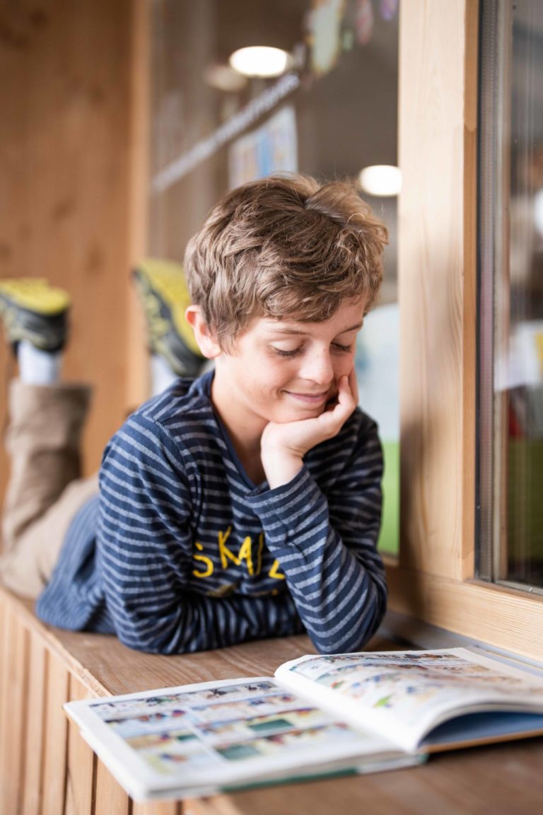 Kind leest aandachtig een boek in de mediatheek van Vaujany.