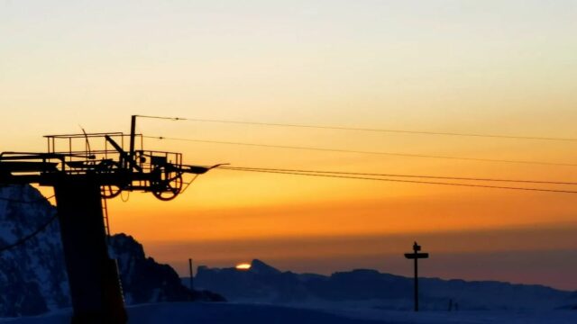 Ski coucher de solei:l : remontée mécanique à contrejour d'un ciel orangé au crépuscule l'hiver