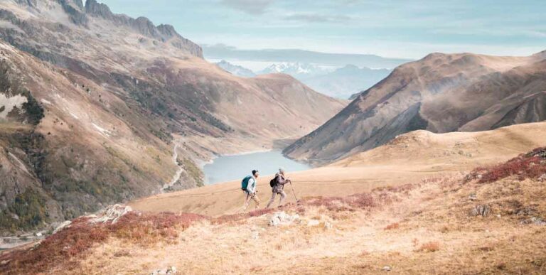 Randonnée pédestre aux couleurs d'automne : 2 randonneurs sur une colline avec le lac de Grand'Maison