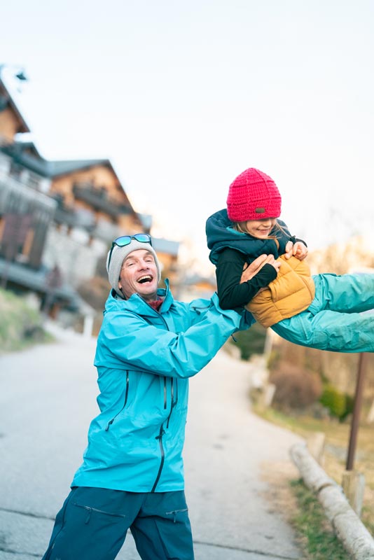 Father with son in winter suit joyfull on the street of Vaujany