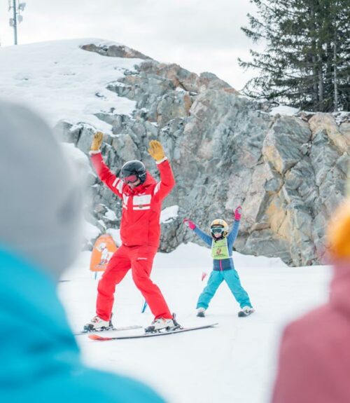 Cours ESF : Moniteur et enfant sur les skis avec les bras en l'air