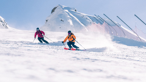 Skieurs en courbes sur les pistes enneigées de Vaujany à la lumière du matin pour la première descente de la journée