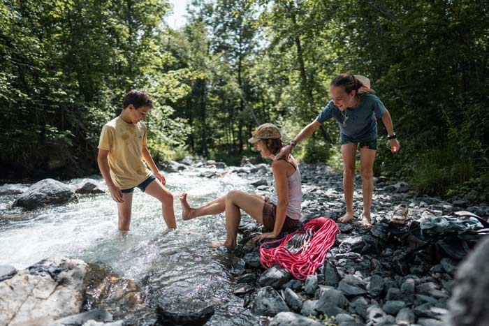 Groupe d'enfants se rafraichissant les pieds dans le torrent après une sortie escalade à Vaujany - Oisans France