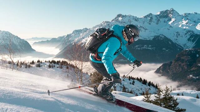 Skieur glissant sur les pentes enneigées de Vaujany face aux massifs recouverts de blanc